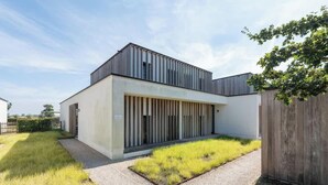Een modern gebouw met een plat dak, grote ramen en een gazon ervoor.