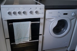 A compact kitchen with a built-in oven and a front-loading washing machine. - Quiet 1-Bed Apartment | Free Parking, Fast Wi-Fi | Ideal for Contractors (Northmuir)