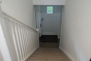 A narrow staircase with a white door at the top, a small window, and a doormat at the bottom. - Quiet 1-Bed Apartment | Free Parking, Fast Wi-Fi | Ideal for Contractors (Northmuir)