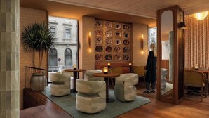 A modern interior with a seating area, a wall decorated with plates, and a view of a building outside. - Casa Aroa Hotel (Barcelona)