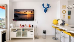 A modern living room with a TV, decorative items, a bar area, and a city view. - La Roca Sea Breeze (Torremolinos)