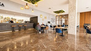 A modern bar area with a marble floor, bar stools, and a counter displaying various bottles. - La Roca Sea Breeze (Torremolinos)