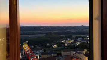 Une vue à travers la fenêtre d’un immeuble, avec des montagnes russes visibles au loin, entourées d’autres immeubles résidentiels et sous un ciel dégagé.