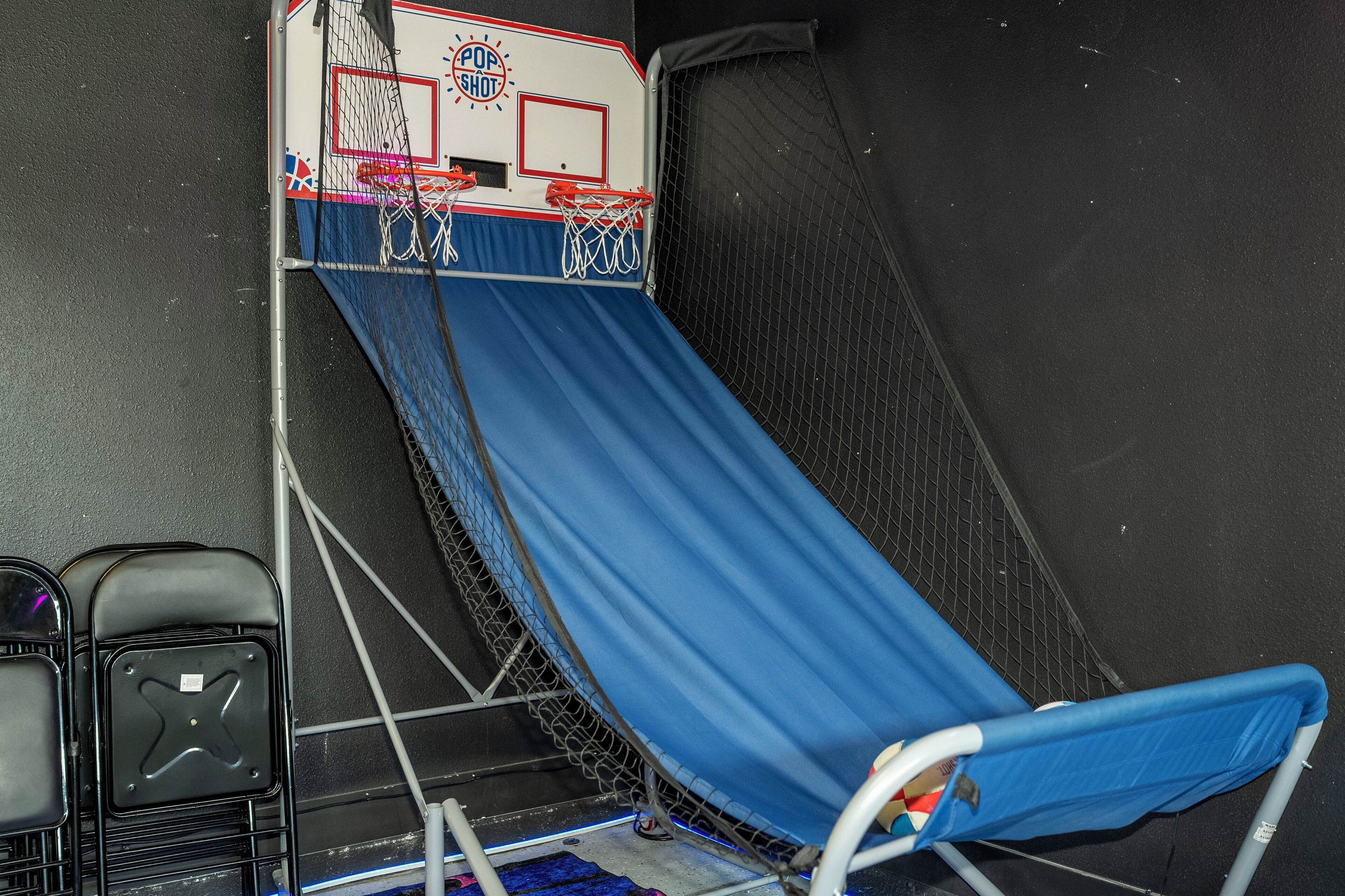 Een blauwe glijbaan met een net bovenop, een basketballen en een muur met een reliëfpatroon.