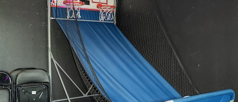 A blue slide with a netted top, a basketball hoop, and a wall with a textured pattern.