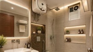 Et moderne badeværelse med et stort spejl, en vask, toilet, brusebad og hylder med toiletartikler.