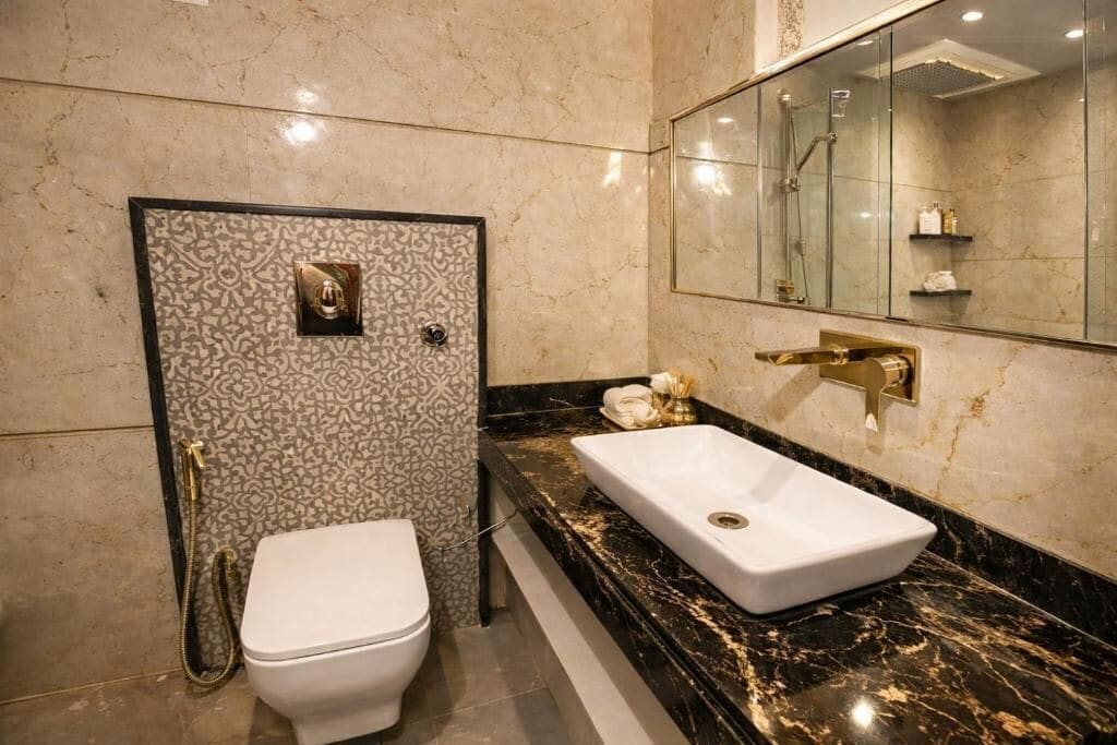 A bathroom with a white toilet, a marble sink, and a glass-enclosed shower area.