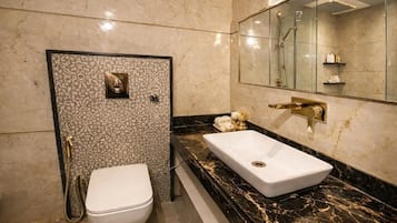 A bathroom with a white toilet, a marble sink, and a glass-enclosed shower area.