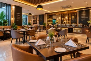 A restaurant with multiple dining tables, chairs, and a bar area. - NH Skye Suites Hotel T-3 Delhi Airport  (New Delhi)
