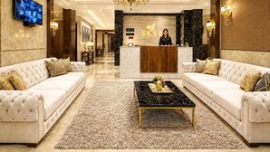 En hotellobby med reception, to sofaer, et sofabord og en lysekrone.