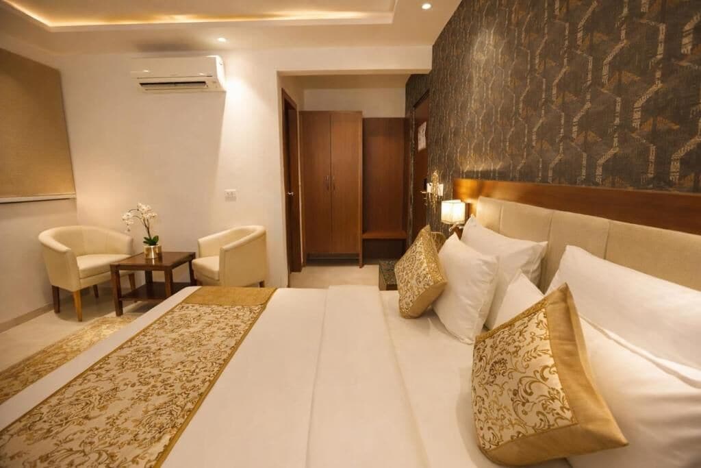 A hotel room with a large bed, two armchairs, a small table, and a decorative rug.