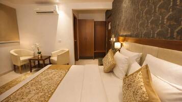 A hotel room with a large bed, two armchairs, a small table, and a decorative rug.