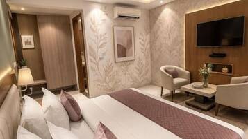 A modern hotel room with a large bed, a flat-screen TV, a seating area, and a ceiling fan.