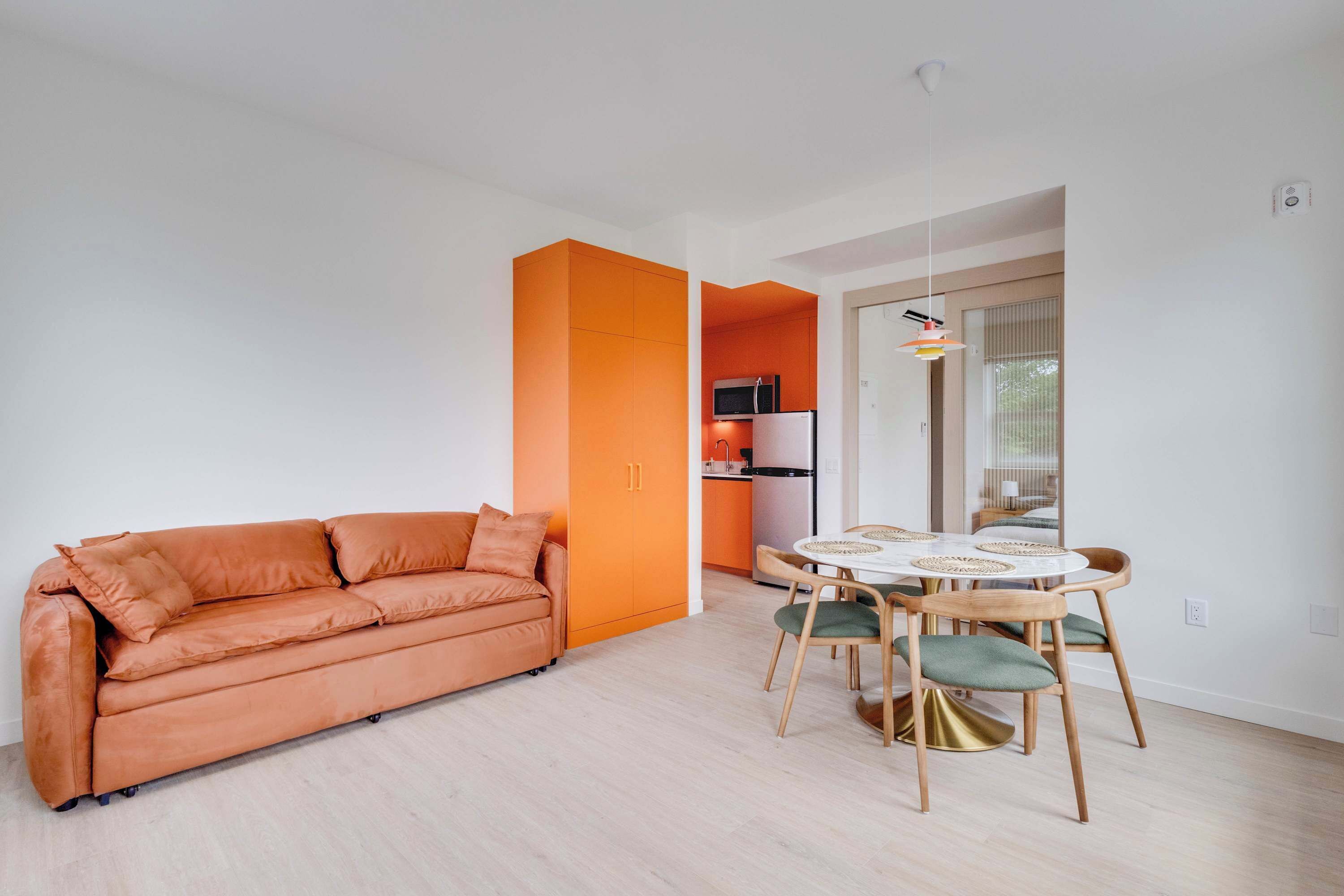 A modern living room with a sofa and a dining area with a table and chairs.