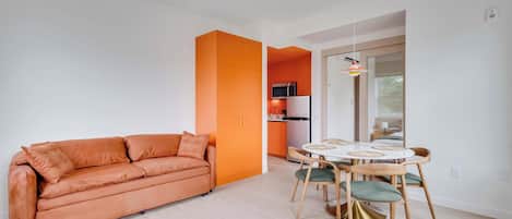A modern living room with a sofa and a dining area with a table and chairs.