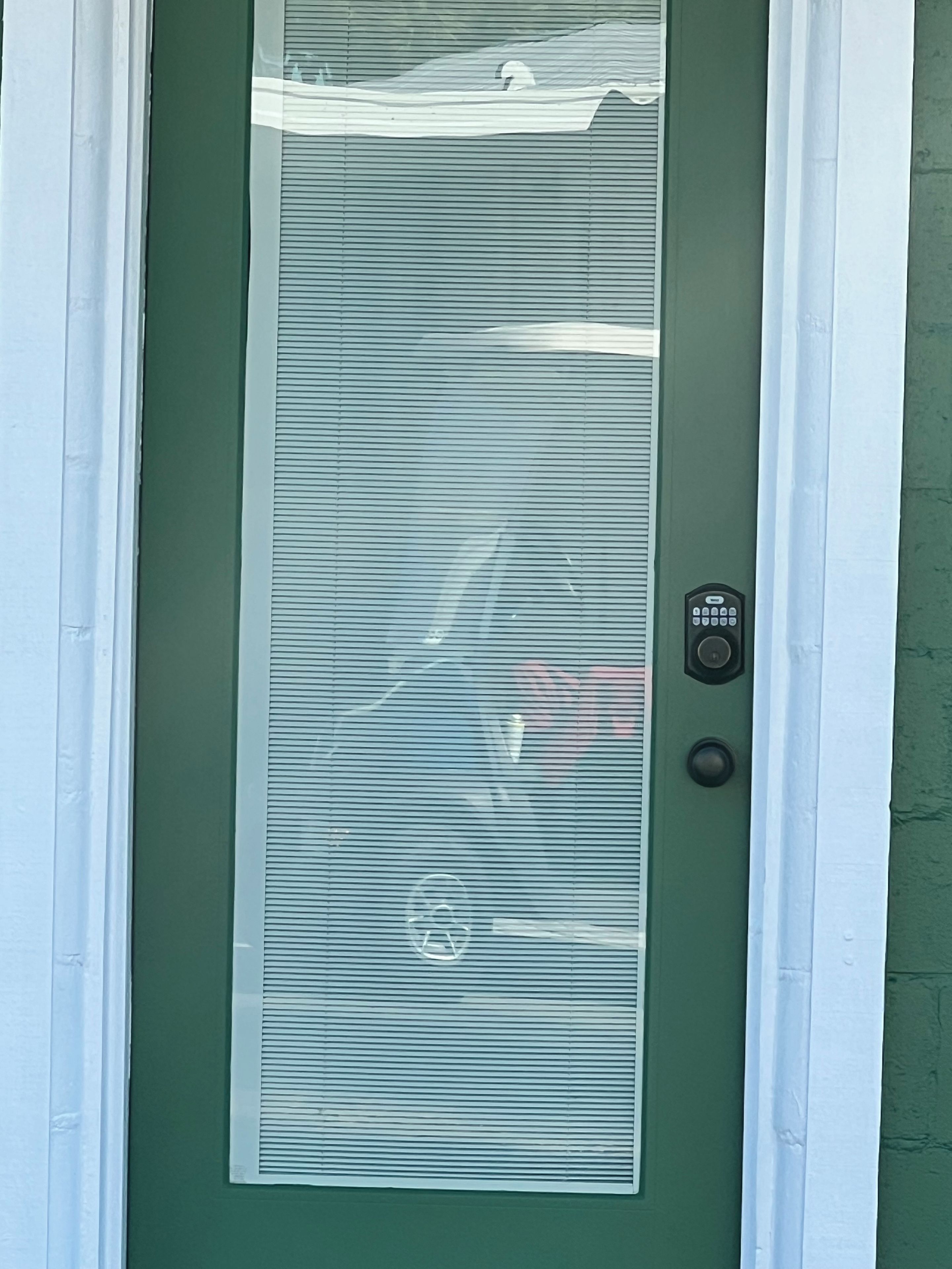 A green door with a frosted glass panel and a keypad lock.