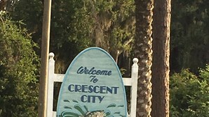 A welcome sign for Crescent City, highlighting it as the Bass Capital of the World, with a historical marker from 1852.
