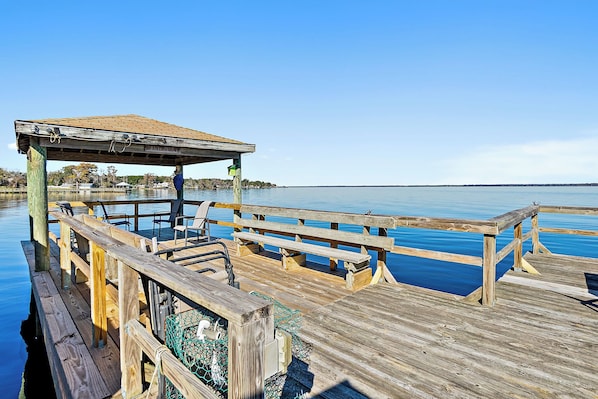 A wooden pier with a covered seating area and a view of calm water.