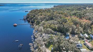 An aerial view of a lakeside property with a dock, boats, and mobile homes.