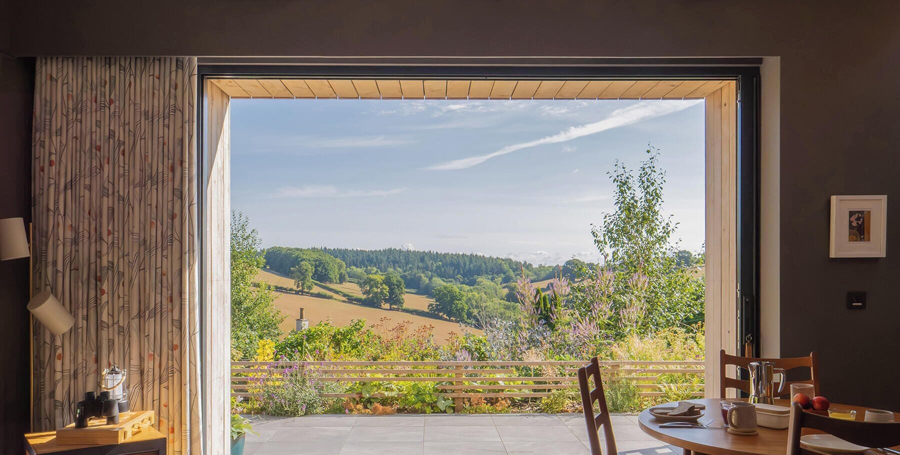 A room with a large window offering a view of a countryside landscape.