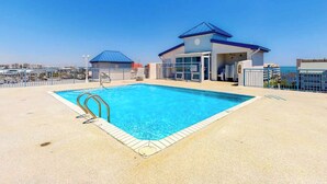 A swimming pool with a blue roof structure, a fenced area, and a clear sky. - Sunset Pointe 302 - Pool, Prime Location (Ocean City)