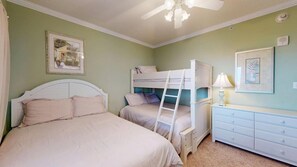 A bedroom with bunk beds, a dresser, a lamp, and a ceiling fan. - Sunset Pointe 302 - Pool, Prime Location (Ocean City)