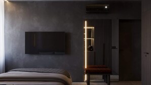 A modern hotel room with a bed, a flat-screen TV mounted on the wall, and a staircase with illuminated handrails. - Amberlight Boutique Hotel Nº13 | Adults Only|Sauna (Gdańsk)