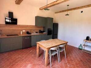 Eine kleine Küche mit Holztisch und -stühlen, einem Geschirrspüler und einem Kühlschrank.