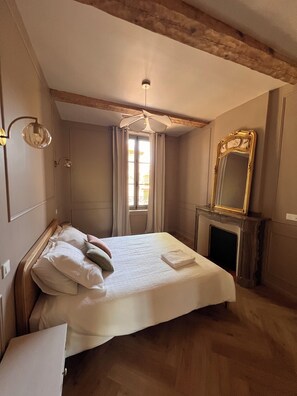 A bedroom with a bed, a mirror, a fireplace, and a window. - 90m2 air-conditioned vacation rental / Pool & Garden / Near the beaches (Fleury)