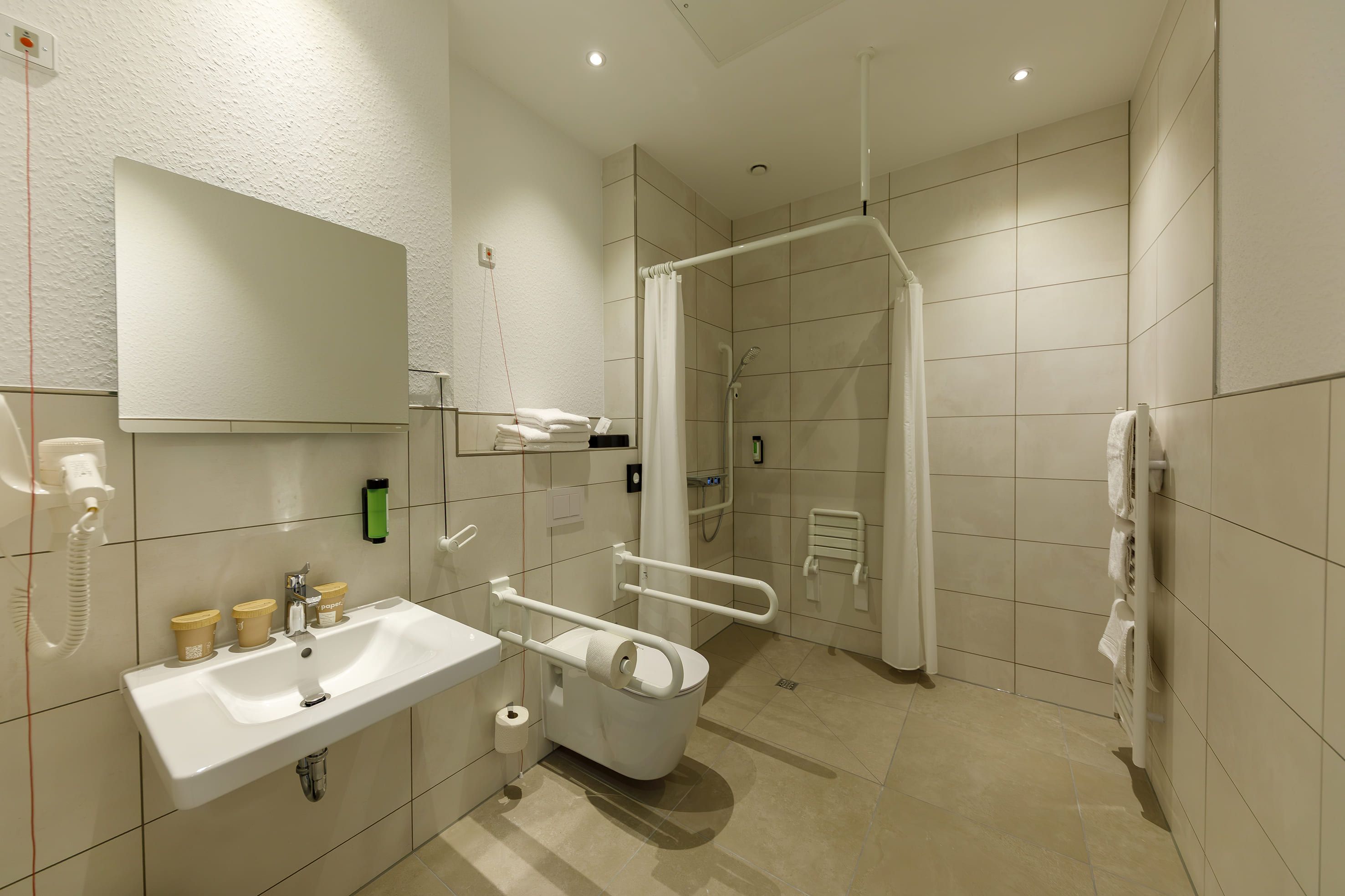 Ein modernes Badezimmer mit Waschbecken, Spiegel und Duschbereich.