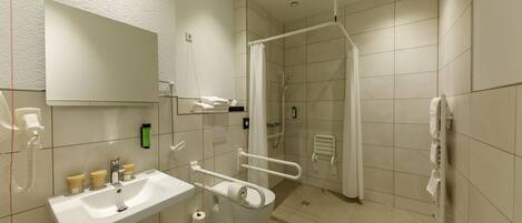 Un baño moderno con lavamanos, espejo y zona de ducha blancos.