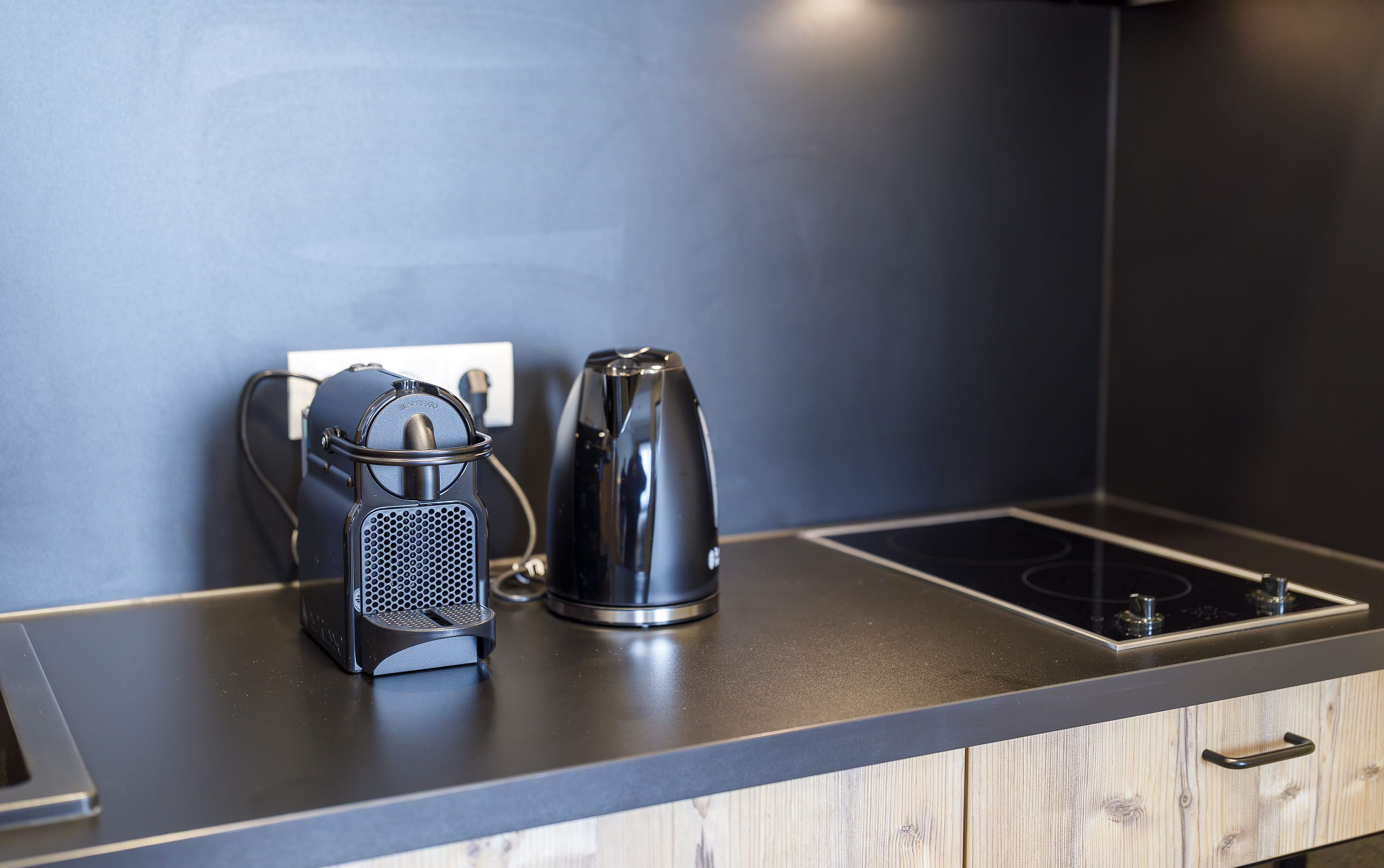 A modern kitchen with a kettle and a coffee maker on the countertop.