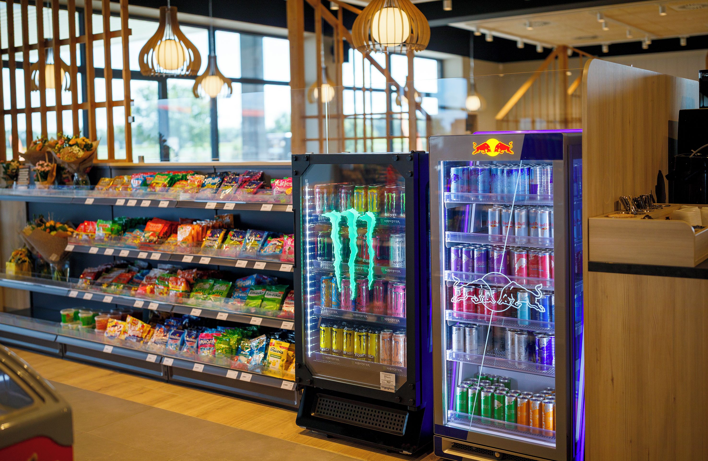A refrigerated display with snacks and beverages, including Monster energy drinks.