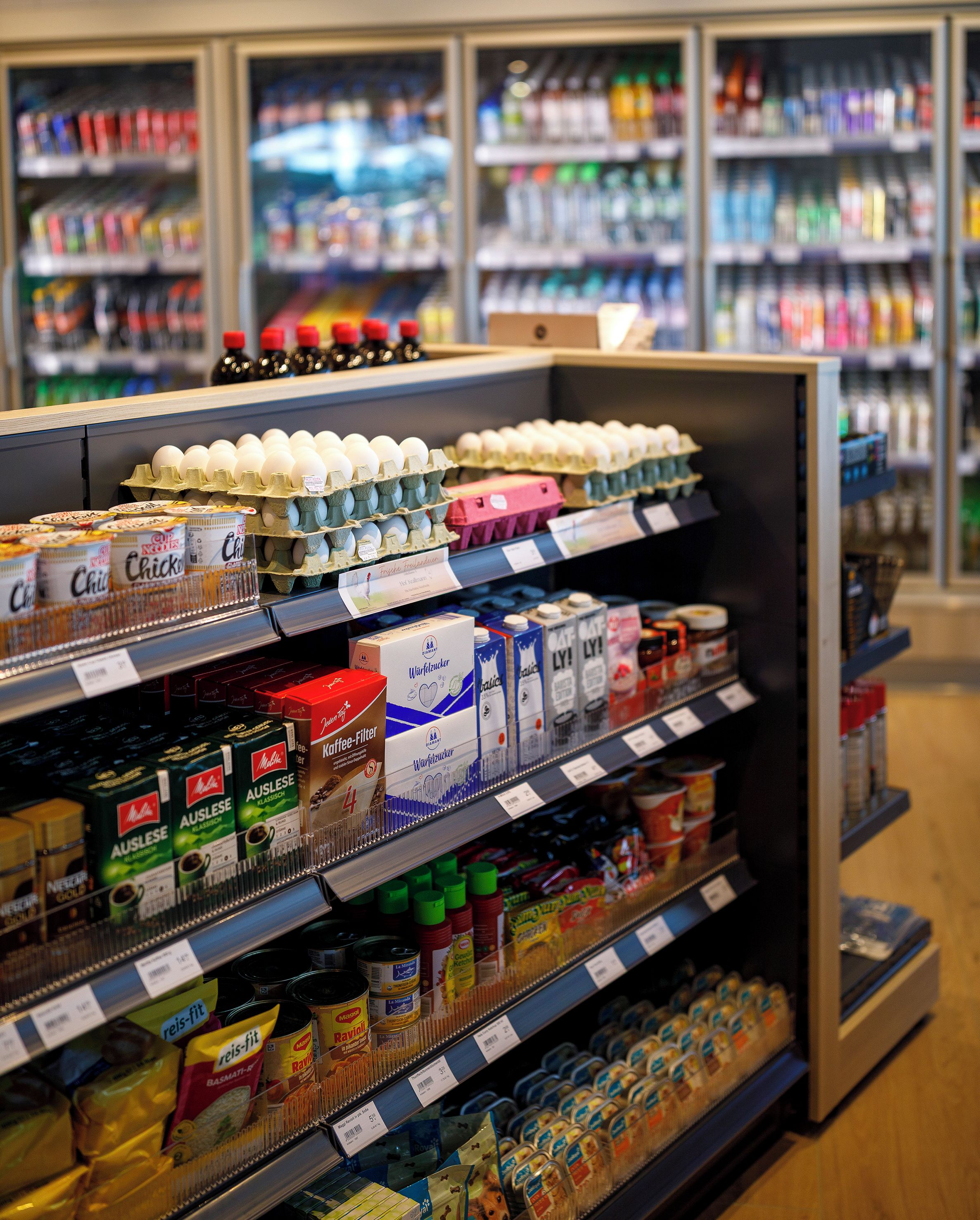 A grocery store aisle with various products including eggs, milk, and coffee.