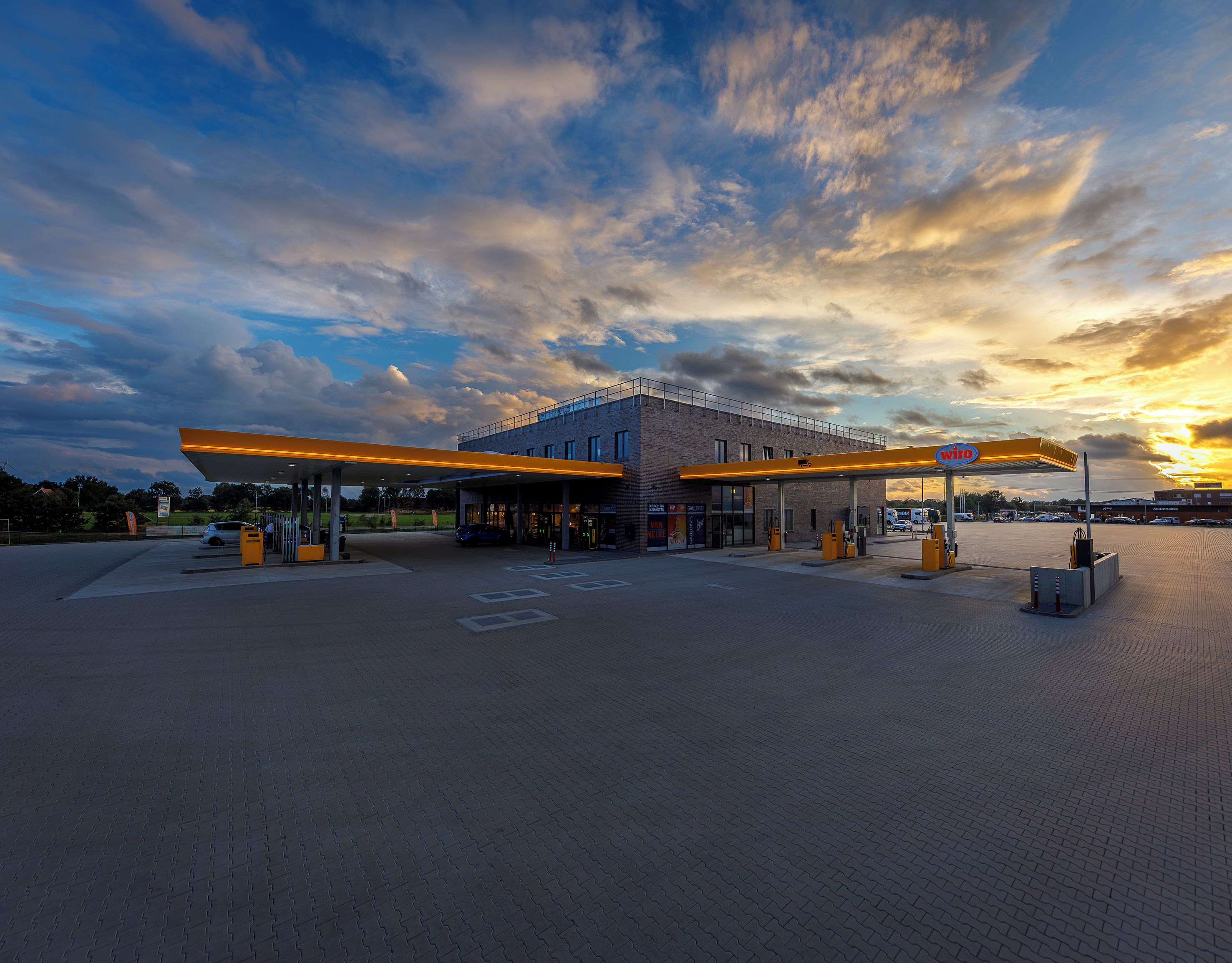 A gas station with a paved parking area, fuel pumps, and a canopy.
