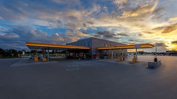 A gas station with a paved parking area, fuel pumps, and a canopy.