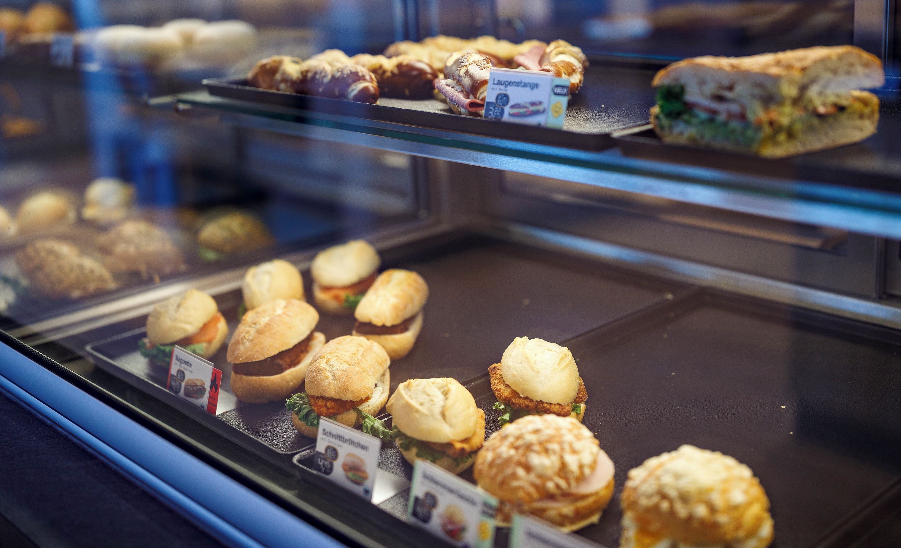 A display case with various baked goods including sandwiches and pastries.