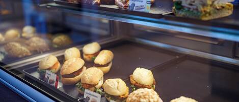 A display case with various baked goods including sandwiches and pastries.
