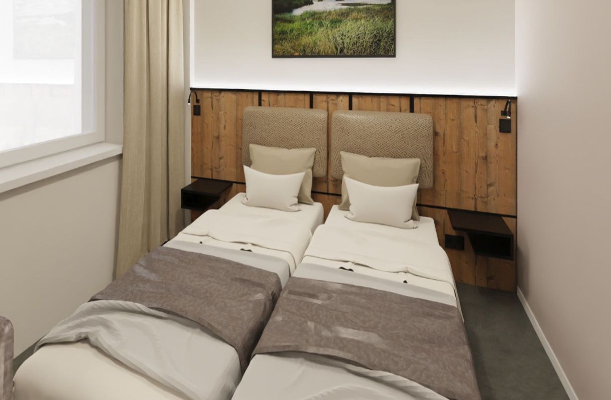 A room with two beds, wooden headboards, a nightstand, and a wall-mounted picture.