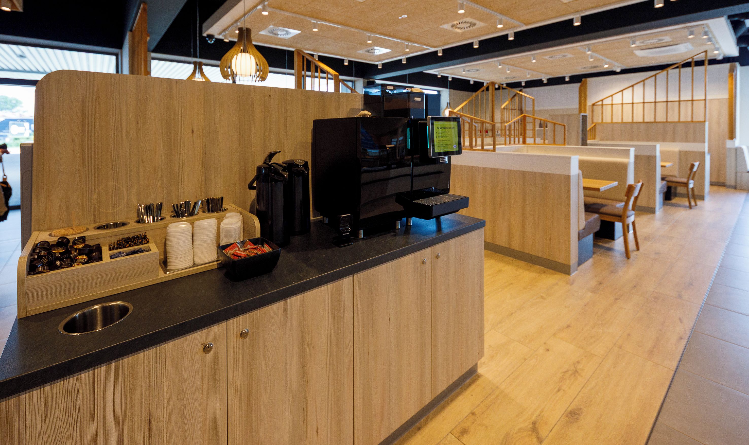 A modern coffee station with a coffee machine, cups, and a bowl of snacks.