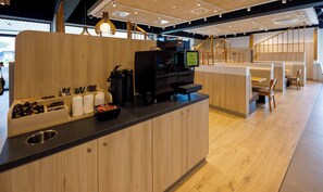 A modern coffee station with a coffee machine, cups, and a bowl of snacks.