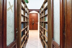 A library hallway with wooden bookshelves on both sides and a tiled floor. - Bovio Apartments in the Heart of Naples - Luna Room (Napoli)