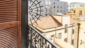 Un balcon doté d’une rambarde en métal et offrant une vue sur les immeubles voisins.