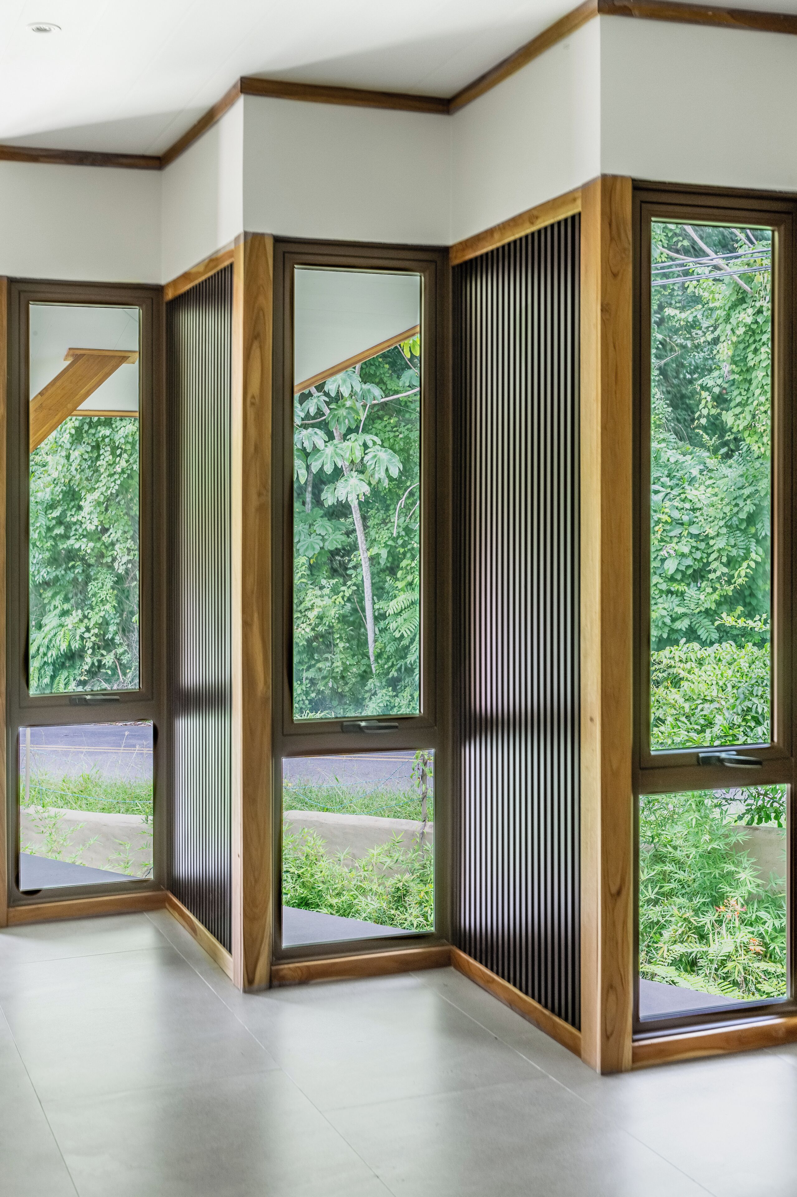 A corner room with large windows, wooden frames, and a view of greenery outside.