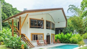 A two-story house with a pool, surrounded by lush greenery. - Relaxing Beachfront vacation in Costa Rica with a pool, overlooking the ocean! (Puntarenas Province)