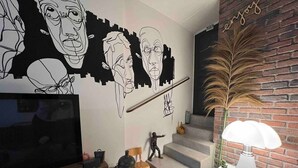 En moderne stue med et fladskærms-tv, en trappe og en dekorativ lampe.