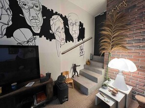 A modern living room with a flat-screen TV, a staircase, and a decorative lamp. - Casa Moz House, Pool, Petanque (Marseille)