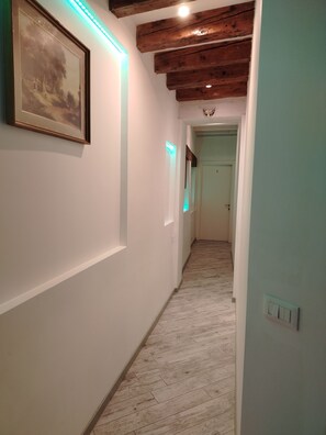 A hallway with a wooden ceiling, a framed picture on the left, and a light switch on the right. - Double Room with Private Bathroom (Venezia)
