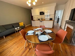 Un coin repas avec une table en bois, quatre chaises et une cuisine en arrière-plan.