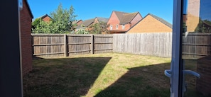 Un jardin avec une clôture en bois, une pelouse verdoyante et un mur en briques.